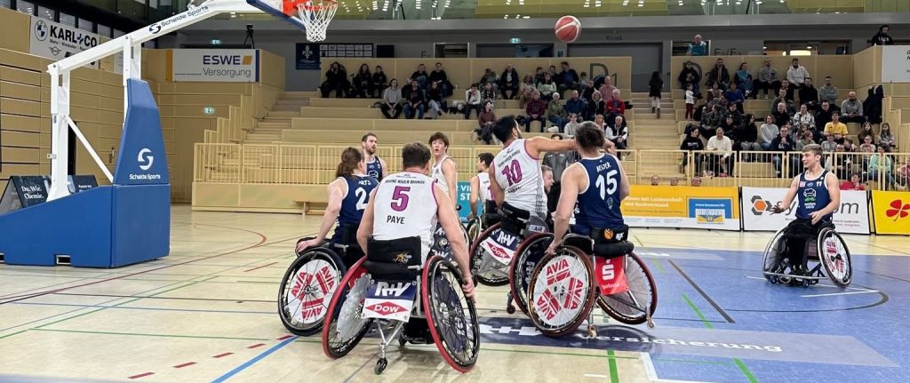 Actionreicher Moment eines Basketballspiels, Spieler dynamisch in Bewegung, kräftige Vereinsfarben, Spannung und Teamgeist spürbar.